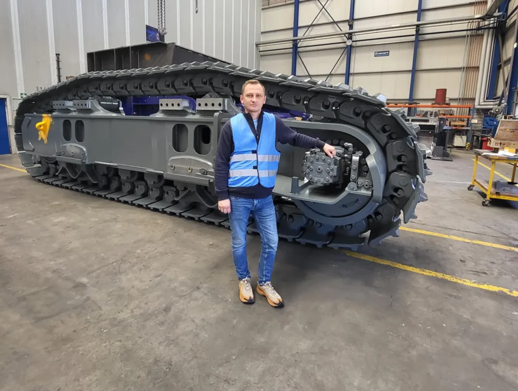 Specialist standing next to a heavy steel track frame in a workshop